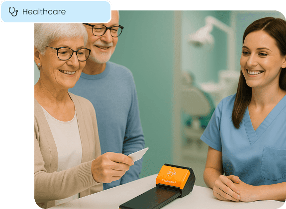 An older couple smiles while making a payment at a healthcare clinic's front desk, illustrating secure and easy payment solutions for medical practices.
